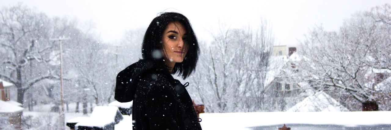woman with short dark hair stands in the snow