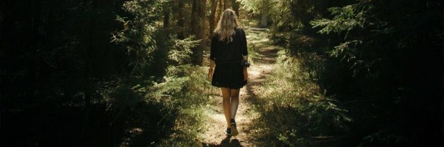 young woman walking along path through forest