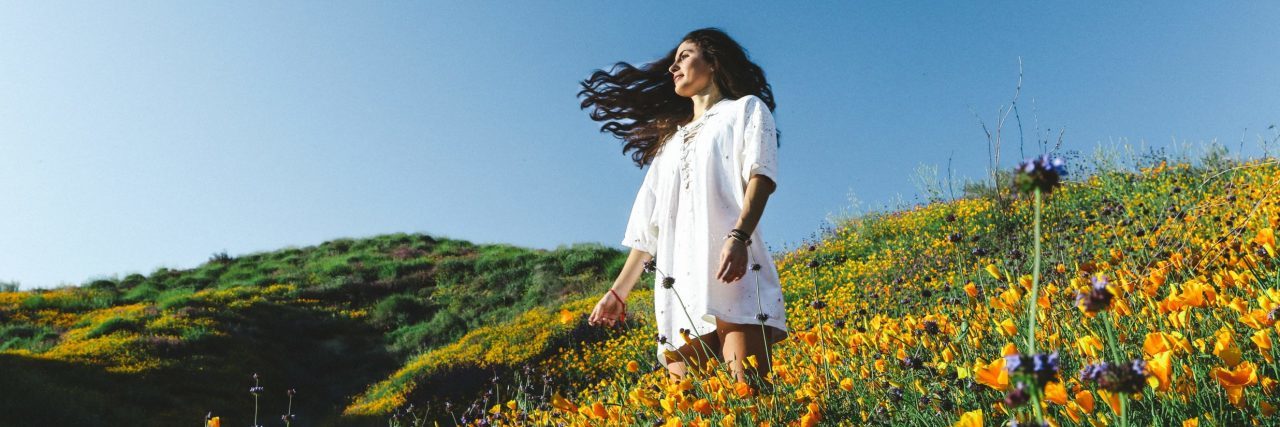 What I Want Anyone Who Self-Harms to Remember in the New Year woman in flower field looking hopeful