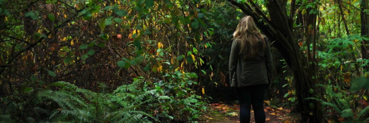 Why Resisting Suicidal Thoughts Doesn't Make Them Less Real woman standing alone by tree at entrance to woods