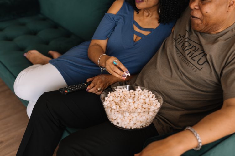 man and woman sitting on couch eating popcorn