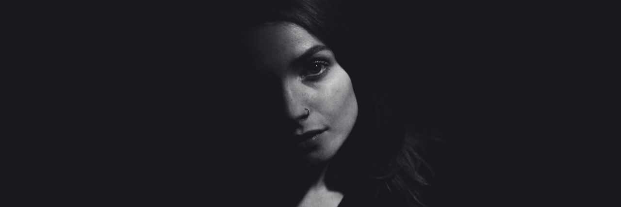 dark portrait of woman with shadow over half of her face
