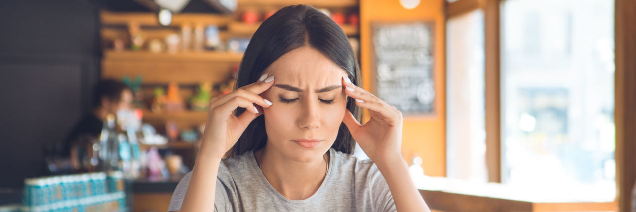 woman getting a migraine at a restaurant