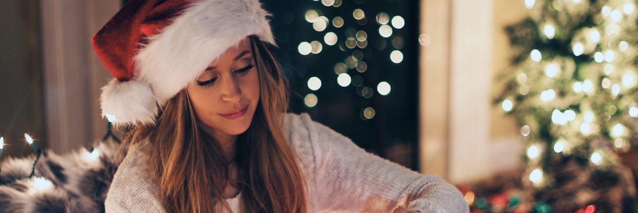 How to Celebrate the Holidays With Depression and No Family woman alone at christmas opening large present