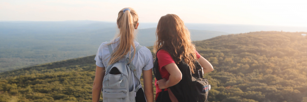 5 Ways I Maintain Friendships With Anxiety and Depression photo of two women hiking and standing on cliff edge looking out over trees