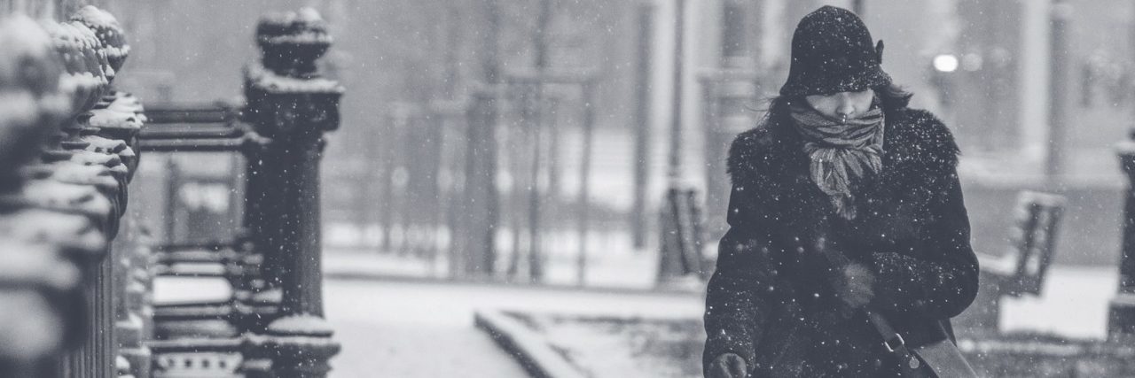 woman walking along street in snowstorm