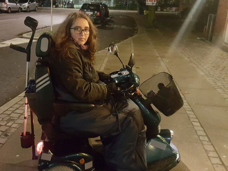 14-year-old girl riding a mobility scooter outside and wrapped up in warm blankets and a coat