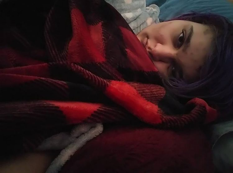 woman lying in bed under a black and red blanket