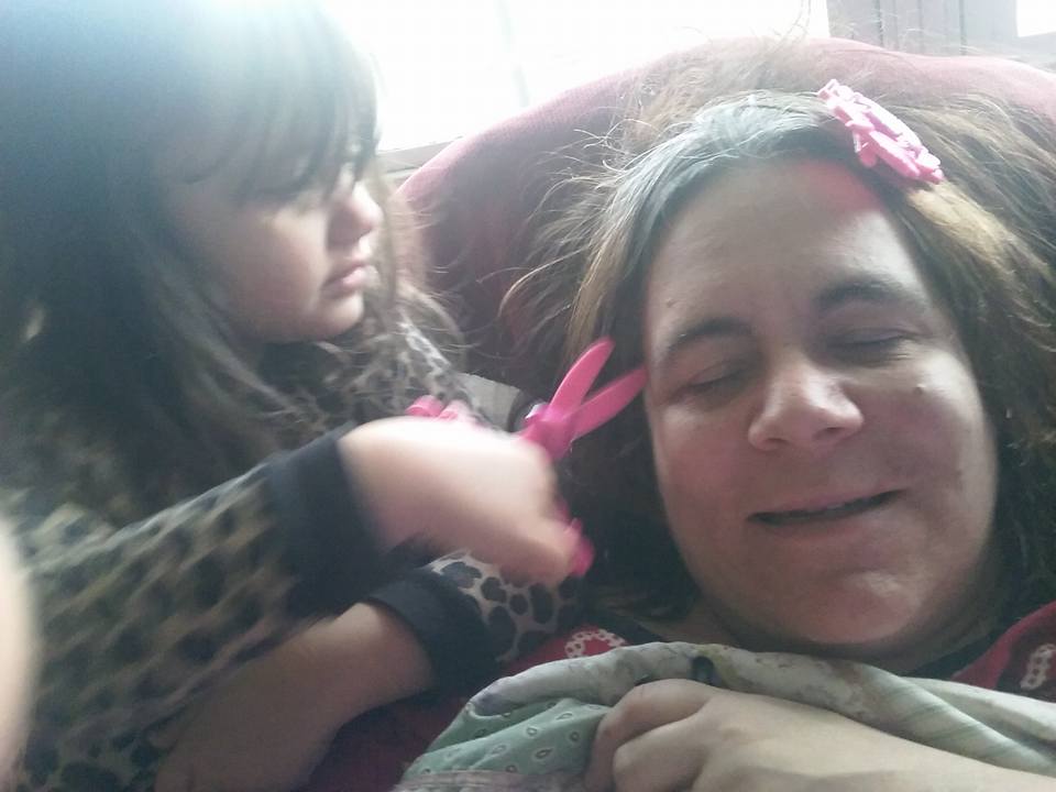 young daughter putting pink clips in her mother's hair
