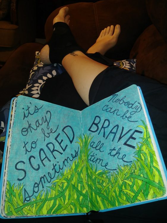 it's ok to be scared sometimes nobody is brave all the time written on paper on woman's legs