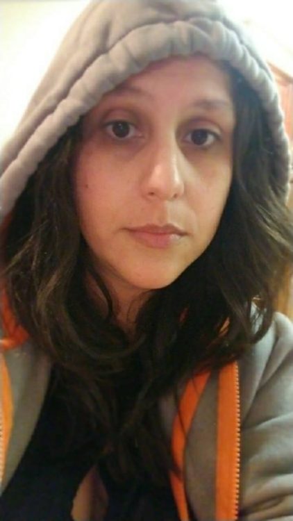 selfie of a woman with dark hair wearing a hoodie and looking tired
