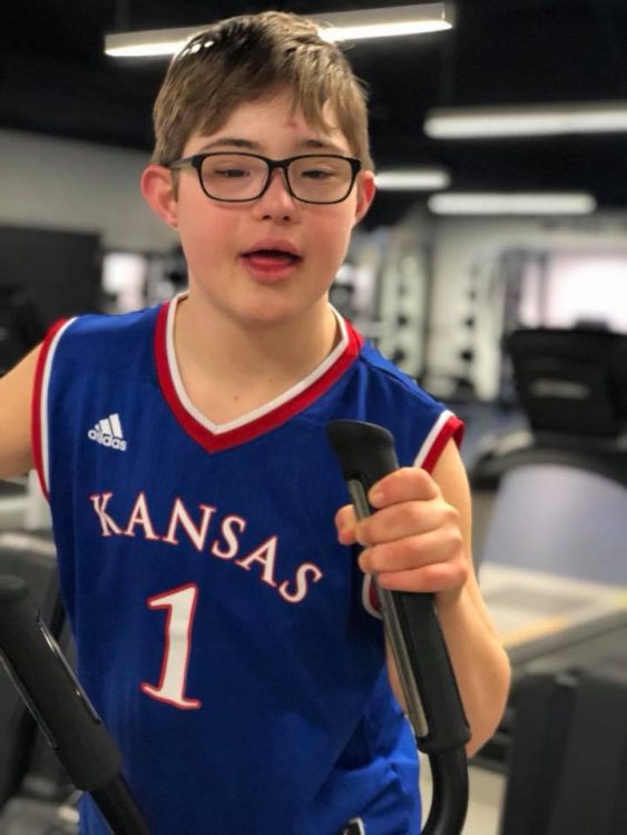 Teenager with Down syndrome wearing a blue basketball jersey "Kansas 1"