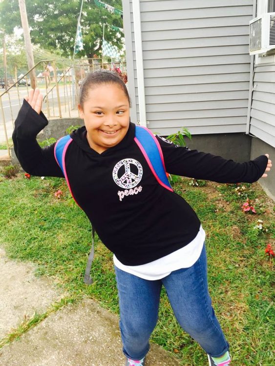 Pre teen with Down syndrome, posing for the camera being silly and wearing her school backpack.