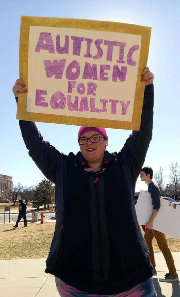 a woman with a sign that says autistic women for equality