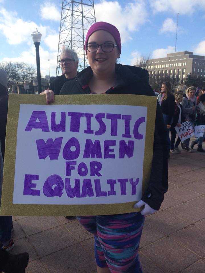 a woman with a sign that says autistic women for equality