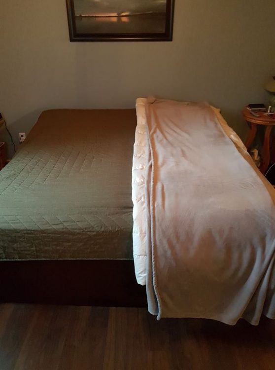 photo of a couple's bed. the left side only has the duvet, while the right side is piled high with blankets and heating pads