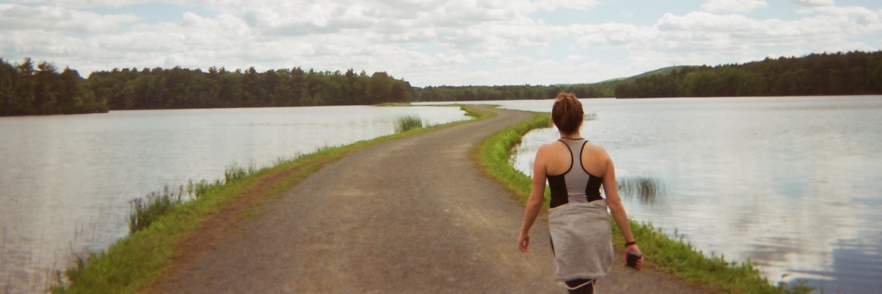 A photo of the writer walking on a pathway surrounded by water.