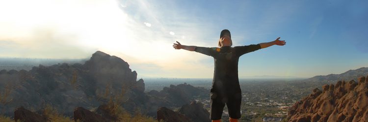 panoramic image of woman standing on a mountain after hiking