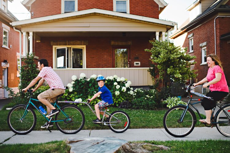 A family riding bikes, mom and dad at the end and son with Down syndrome in the middle.