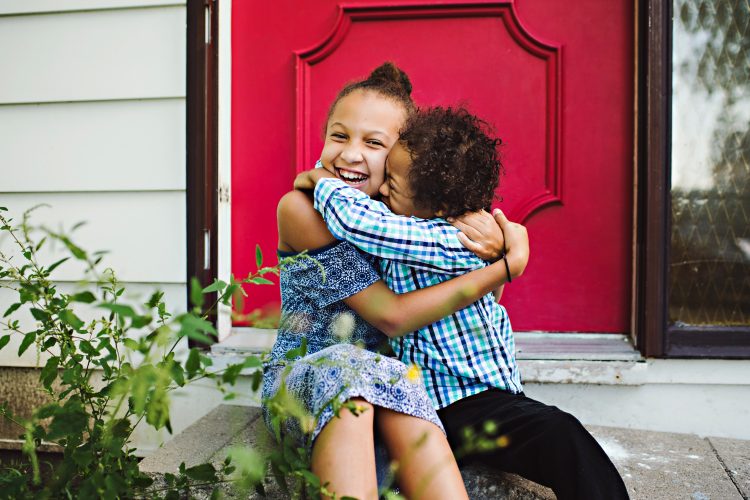 Siblings hugging. Brother has Down syndrome, both are happy.