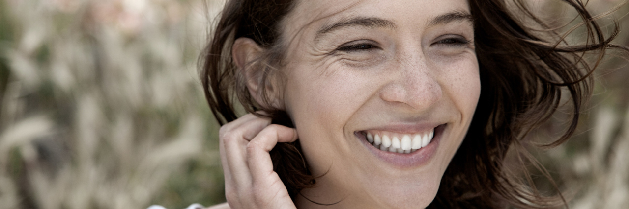 woman laughing and tucking her hair behind her ear