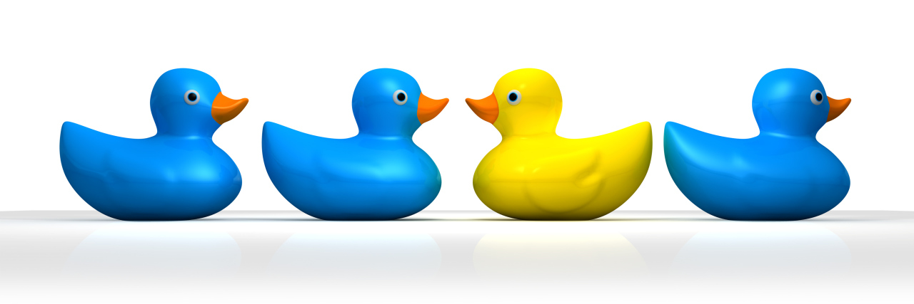 Autism and Feeling Like a Misfit Among Misfits Yellow rubber bath duck swimming in a different direction to the other three blue ducks
