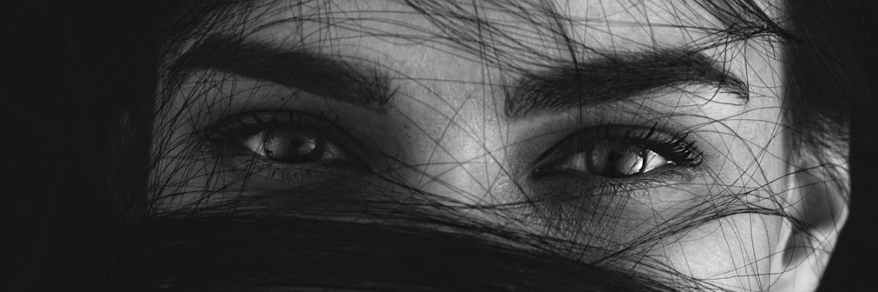 When I Say I'm 'Fine,' I'm Not in Denial About Being Sick A portrait of a woman with hair wrapped around her face.