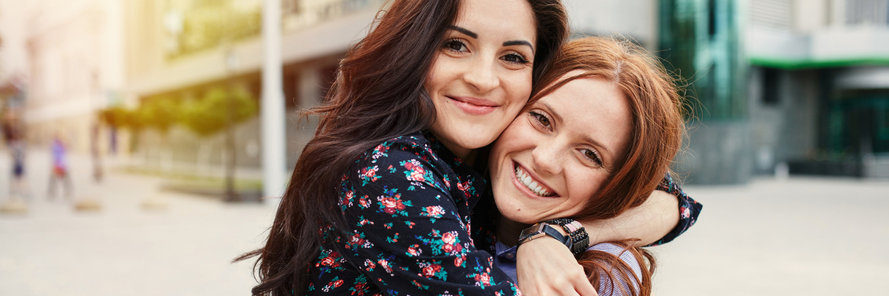 two women hugging one another and smiling