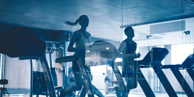 Active young people running on treadmills in sports club