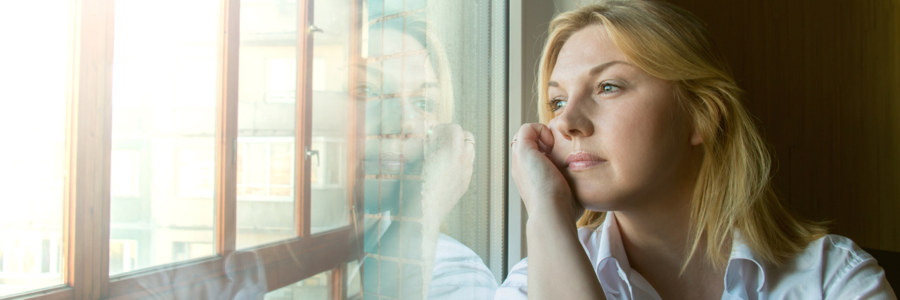 Woman looking out window lost in thought rumination
