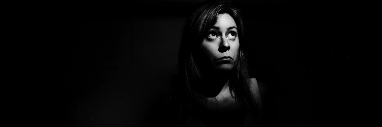 The World Doesn't Feel Safe When Living With Primary Immunodeficiency A woman in the shadows, looking afraid.