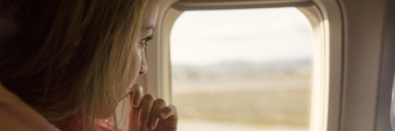 The Difference Between a Panic Attack and a Moment of Panic woman looking out of plane window nervous scared