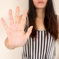 Young woman holding her hand up to say "no."