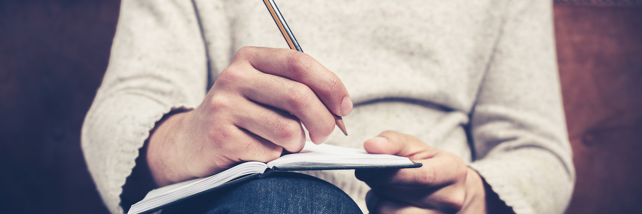 A Letter to Those Who Don't Understand Depression A man is sitting on a sofa and writing notes in a notebook