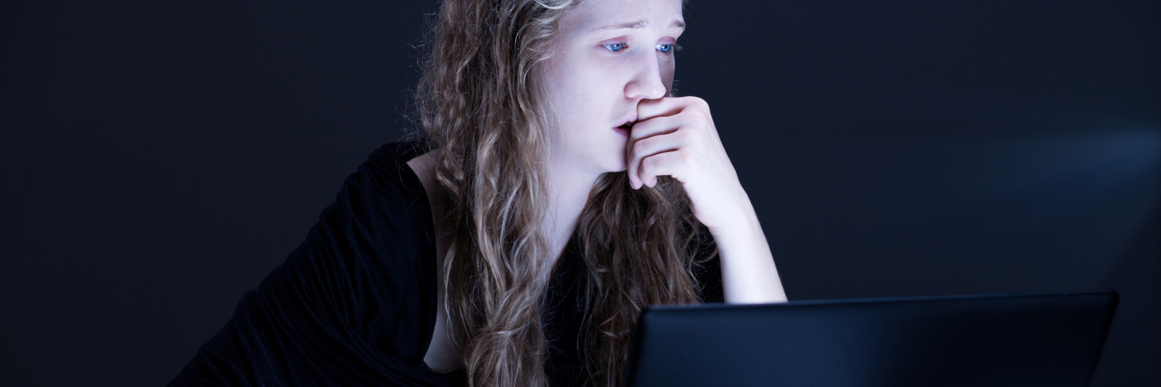 young woman crying in front of laptop computer