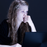 young woman crying in front of laptop computer