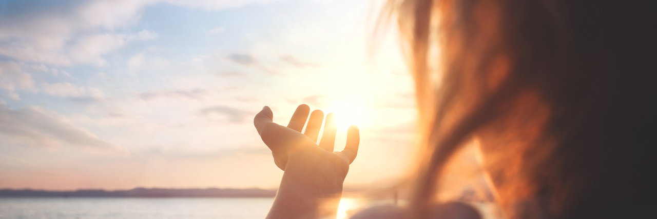 Finding the Silver Lining of Lyme Disease A woman outside near a body of water, during the sunset.