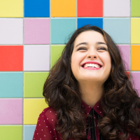 Happy girl laughing against a colorful tiles background. Concept of joy
