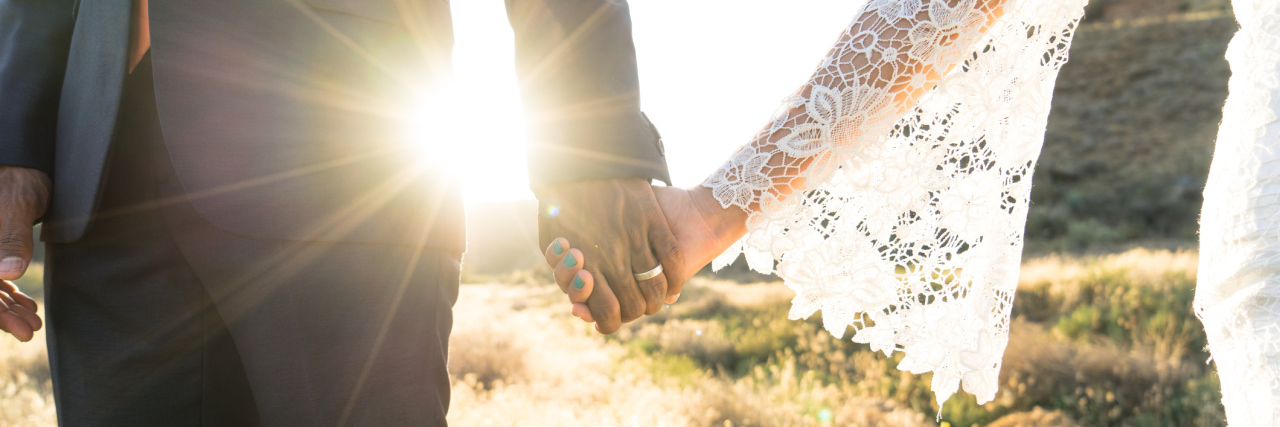 9 Relationship Tips When Both Partners Are Sick An Interracial couple holding hands backlit by the flaring sun