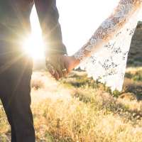 An Interracial couple holding hands backlit by the flaring sun