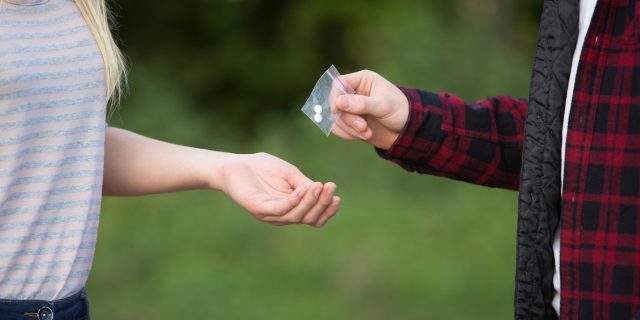 A woman taking pills from another person.