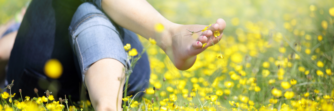 woman lying in meadow of buttercups barefoot