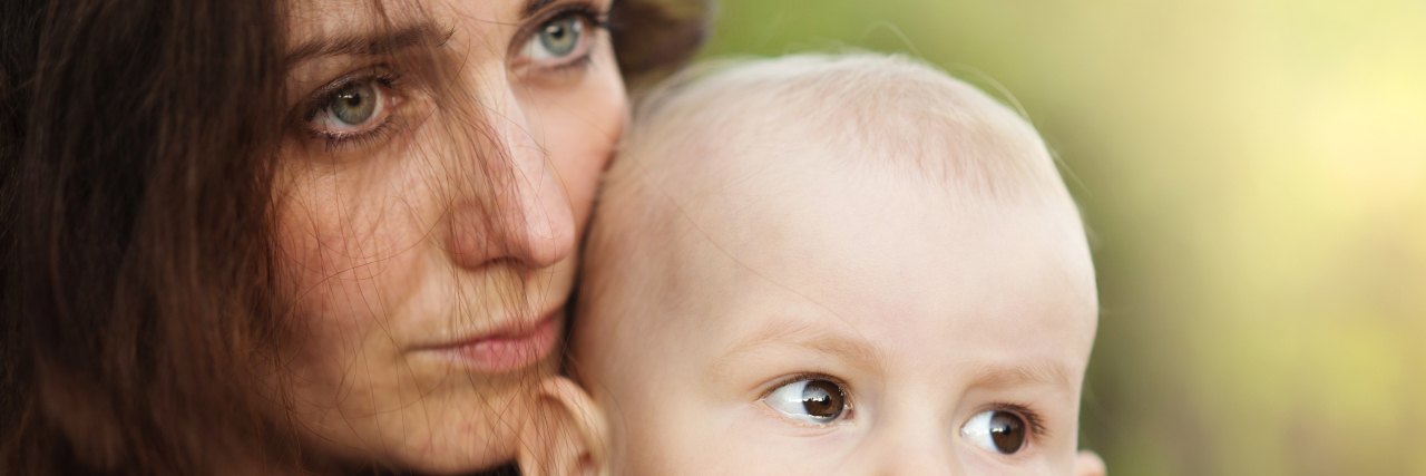 How Postpartum OCD Made Me Question My Entire Life Portrait of a crying little boy who is being held by her mother, outdoors