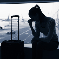 A stressed out silhouette of a woman at an airport with an airplane blurred behind her.