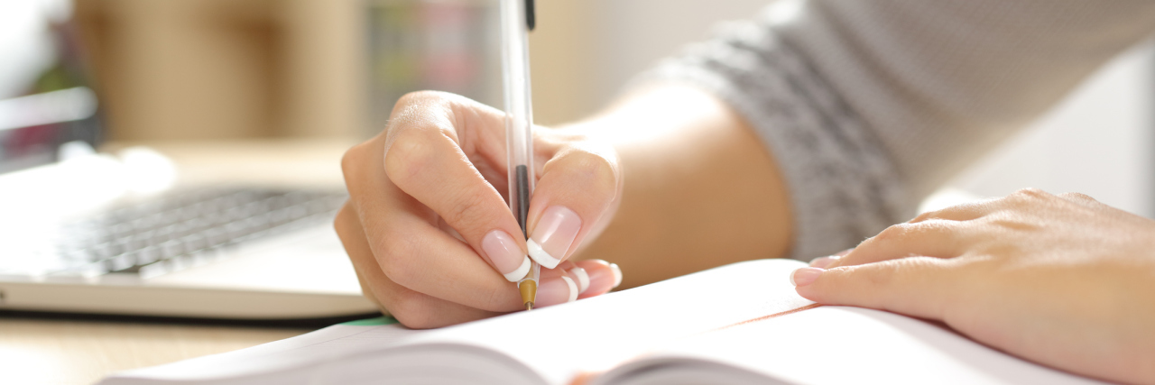 A close-up of a woman writing in a notebook.