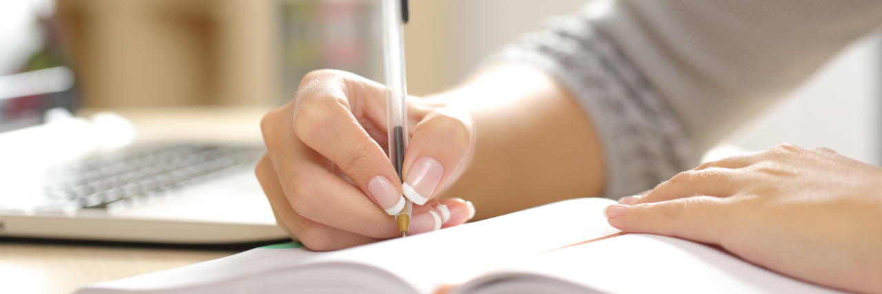 Strategies That Can Help You Achieve Your Goals If You're Ill A close-up of a woman writing in a notebook.