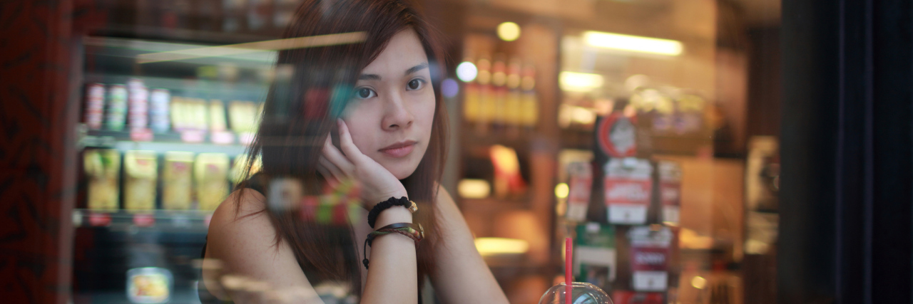 How Having Autism Affects My Depression young woman in cafe at night with depression looking out of window