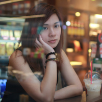 young woman in cafe at night with depression looking out of window