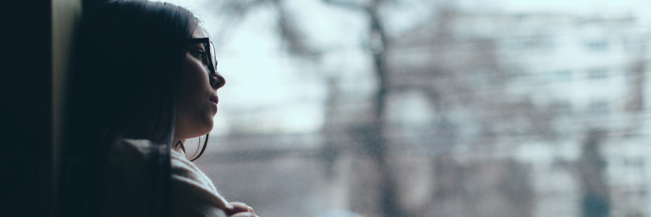 How a Career-Ending Injury Lead to a Diagnosis A woman looking out a window with a depressed expression.