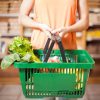 woman holding a grocery basket full of vegetables